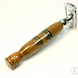 Puede incluir: Una navaja de afeitar de seguridad cromada con mango de madera. El mango es marr&oacute;n con detalles en negro y dorado.