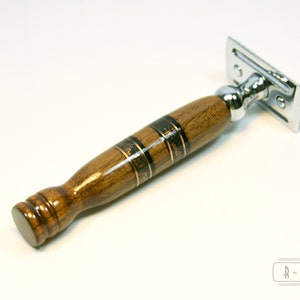 Puede incluir: Una maquinilla de afeitar de seguridad con una cabeza cromada y un mango de madera. El mango es marr&oacute;n con detalles en negro y dorado.