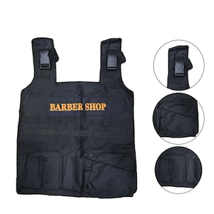Peut inclure: Tablier de barbier noir avec plusieurs poches et sangles réglables. Le mot "BARBER SHOP" est imprimé en orange sur le devant. Comprend plusieurs petites poches et de grandes pochettes pour les outils.