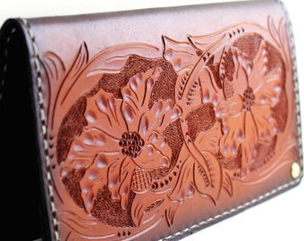 May include: A brown leather wallet with a floral design embossed on the front. The wallet has a flap closure and is stitched with white thread.