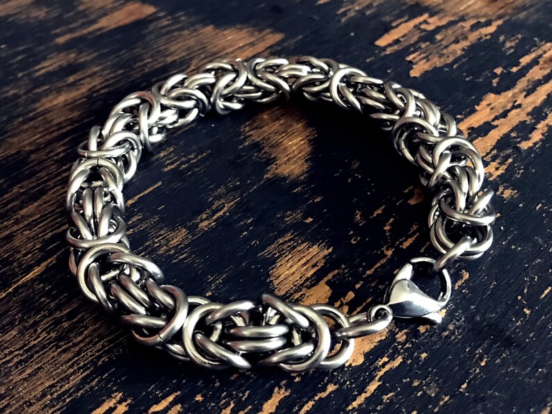 May include: A silver chain bracelet with a lobster clasp closure. The bracelet is made of interlocking metal rings.