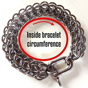 May include: Silver chainmail bracelet with a clasp. The inside circumference of the bracelet is marked with a red circle.