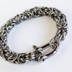 May include: A silver stainless steel bracelet with a woven chain design and a lobster clasp closure.