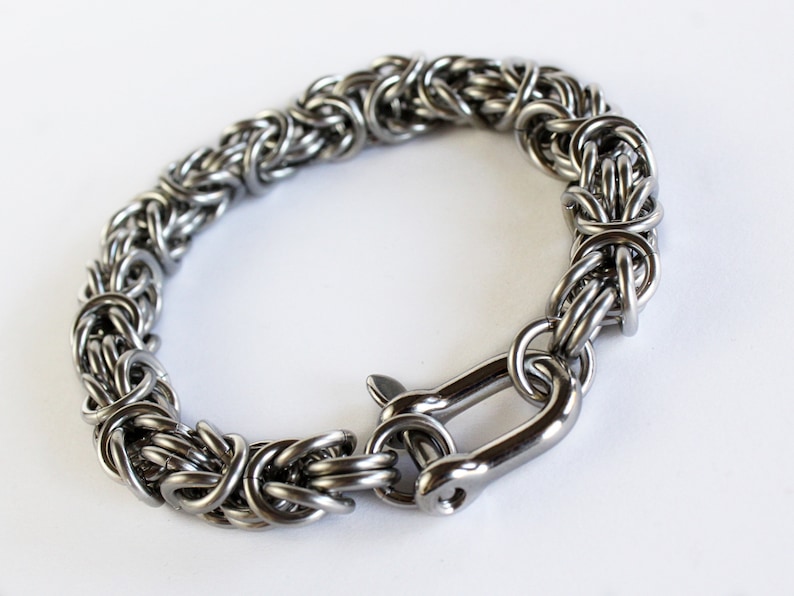 May include: A silver stainless steel bracelet with a woven chain design and a lobster clasp closure.