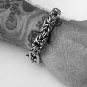 May include: A silver chain bracelet with a clasp closure. The bracelet is made of interwoven metal links.