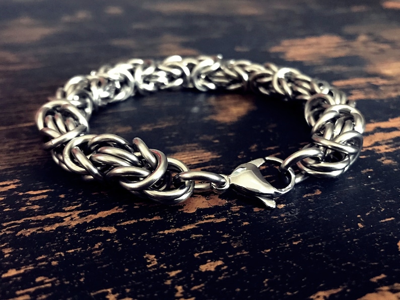 May include: A silver chain bracelet with a clasp closure. The bracelet is made of interwoven metal links.