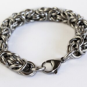 May include: A silver chain bracelet with a lobster clasp closure. The bracelet is made of interlocking metal rings.