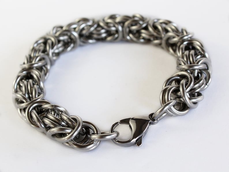 May include: A silver chain bracelet with a lobster clasp closure. The bracelet is made of interlocking metal rings.