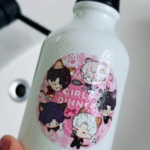 Può includere: Borraccia bianca con manico nero e adesivo rosa. L'adesivo presenta personaggi di gatti dei cartoni animati con la scritta "GIRL DINNER". La bottiglia è ricoperta di goccioline d'acqua.