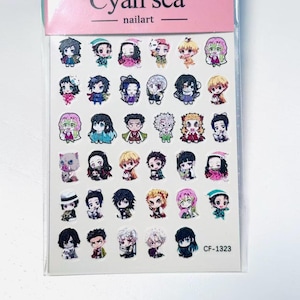 Puede incluir: Una lámina de pegatinas para uñas con diseños de personajes de anime. Las pegatinas son coloridas y detalladas, con varias poses y expresiones. El embalaje es rosa y tiene el texto "Cyan sea nailart". El código de producto es CF-1323.
