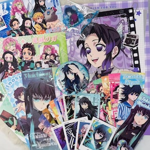 Könnte beinhalten: Eine Sammlung von Anime-Merchandise-Artikeln mit Charakteren aus "Demon Slayer". Die Artikel umfassen Postkarten, Ansteckbuttons, einen transparenten Acryl-Anhänger und einen großen Druck mit dem Text "WISH FOR YOU". Die Farbpalette ist lebendig mit Rosa, Lila und Blau.