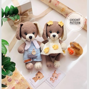 Könnte beinhalten: Zwei gehäkelte Hundepuppen, eine mit blauen Latzhosen und einer weißen Weste, die andere mit einem weißen Kleid mit gelben Blumenakzenten. Die Puppen haben braunes Fell, Schlappohren und schwarze Augen. Der Text "CROCHET PATTERN" ist enthalten.