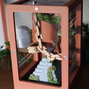 Jumping spider enclosure with front door open, showcasing Aztec temple-style 3D-printed decor, wood-effect hide with built-in hiding spot, magnetic rock ledges, and pet-safe natural moss