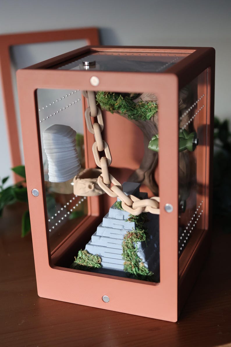 Jumping spider enclosure with front door open, showcasing Aztec temple-style 3D-printed decor, wood-effect hide with built-in hiding spot, magnetic rock ledges, and pet-safe natural moss