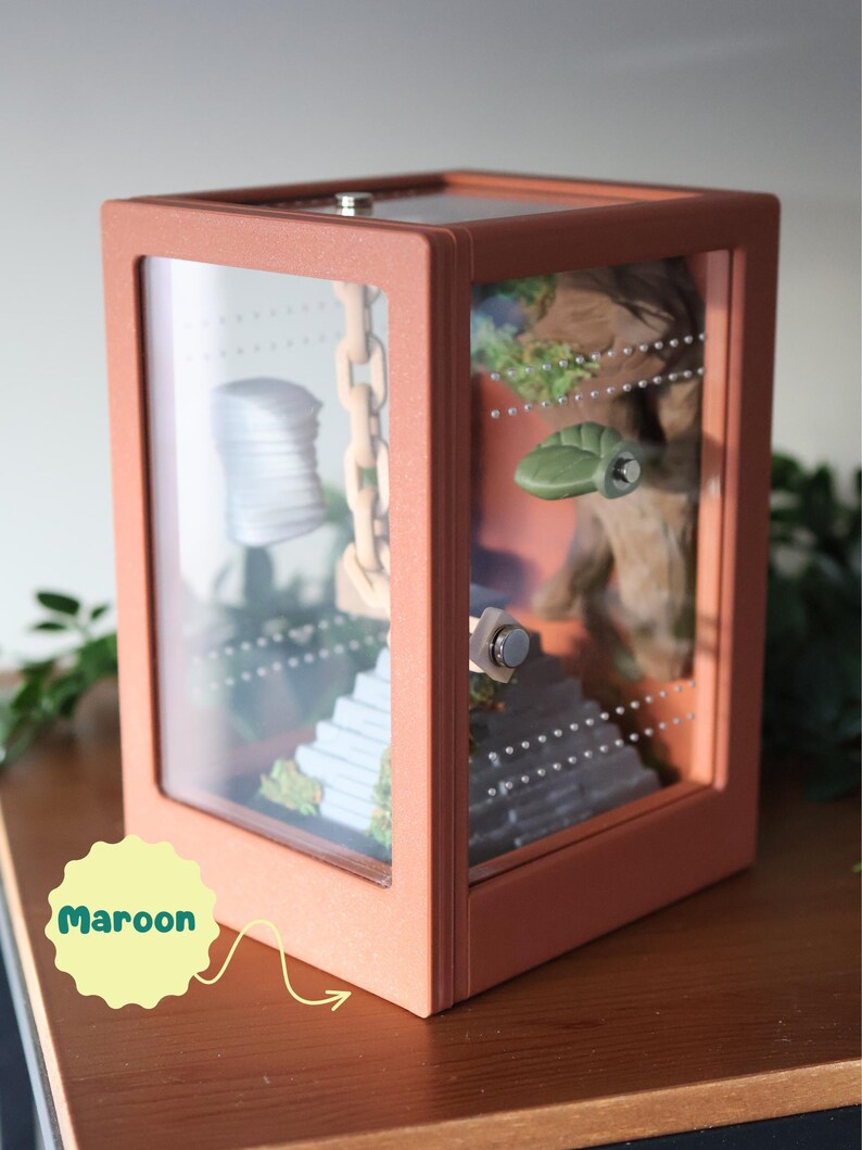 Side view of a matte green 3D-printed jumping spider enclosure, showing ventilation vents on sides and top edge, with natural moss and integrated decorative elements