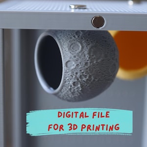 Op de afbeelding: Een grijs, bolvormig object met een getextureerd oppervlak dat lijkt op maankraters, opgehangen in een lichtgrijs frame. Een blauwgroene rechthoekige afbeelding met rode tekst DIGITAL FILE FOR 3D PRINTING staat onder de bol.
