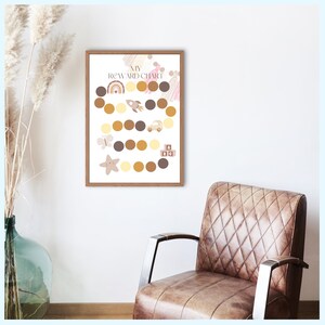 Może przedstawiać: Oprawiony wykres nagród z napisem "MY REWARD CHART" na górze. Wykres zawiera serię kół w odcieniach brązu i żółci, z ilustracjami tęczy, rakiety, samochodu, motyla, gwiazdy i klocków.