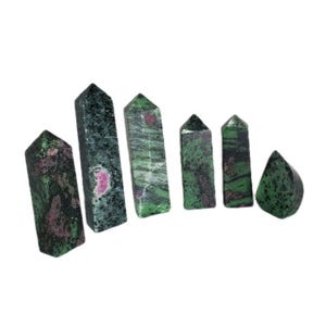 May include: Six polished ruby in zoisite crystal towers. The crystals are a mix of dark green and black with red and pink inclusions. The crystals are various sizes and shapes, with pointed tops and smooth sides.