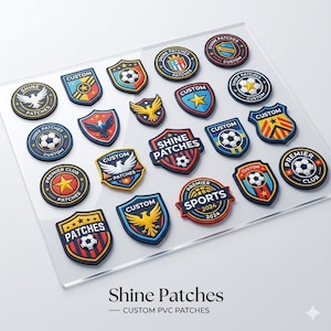 May include: A selection of custom PVC patches in shield and circular designs. The patches display soccer balls, stars, eagles, and text including "Shine Patches" and "Premier Sports 2024". They are in red, blue, yellow, and white.