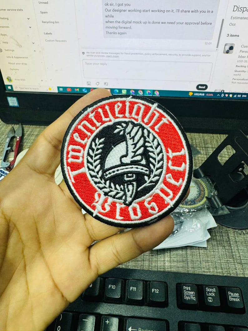 May include: A round, embroidered patch with a red border and black and white center design. The patch features the text "TWENTY EIGHT BROTHERS" in a circular pattern around a central emblem. The emblem includes a helmet and laurel leaves.