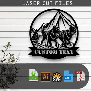 May include: Black metal wall art featuring a dog sled team pulling a sled through a mountain landscape. The design includes the text "LASER CUT FILES" at the top and a banner with "CUSTOM TEXT" at the bottom. Includes file type icons.