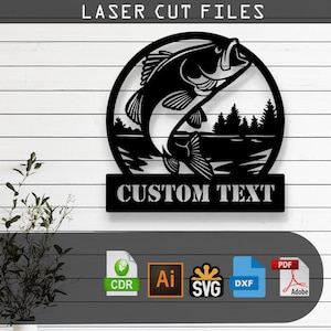 Puede incluir: Archivo de corte láser de metal negro que presenta un pez lubina saltando dentro de un marco circular, con el texto "CUSTOM TEXT" debajo. El diseño incluye una escena de lago con árboles. La parte superior de la imagen dice "LASER CUT FILES".