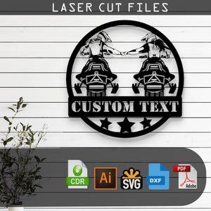 以下が含まれることがあります： 黒い金属製の壁掛けアート。2台の雪上バイクと手を繋ぐライダーが円形のフレーム内に描かれています。「LASER CUT FILES」の文字が上部にあり、下には「CUSTOM TEXT」があります。ファイルタイプのアイコンも含まれています。