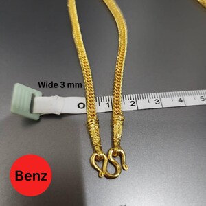 May include: A gold-colored chain necklace with a woven design, 3 mm wide, featuring an S-hook clasp. The word "Benz" is in a red circle. A ruler is next to the necklace.