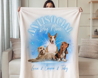 May include: A light-colored blanket featuring three dogs: a Bull Terrier, a Goldendoodle, and a Basset Hound. The blanket has the text "ANTISOCIAL Dog Mom" and the names "Luna & Cooper & Toby" in a light blue color.