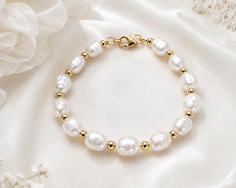 May include: A bracelet featuring alternating white freshwater pearls and small polished gold-tone metal beads. The circular jewelry piece is secured with a gold-tone lobster claw clasp, showcasing a classic design with a lustrous finish.