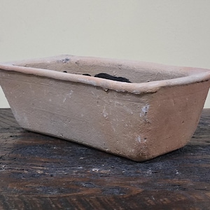 May include: A rectangular terracotta planter with a slightly rough texture. The planter is empty and has a light brown color.