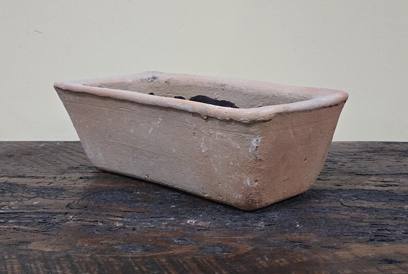 Puede incluir: Un macetero rectangular de terracota con una textura ligeramente rugosa. El macetero est&aacute; vac&iacute;o y tiene un color marr&oacute;n claro.