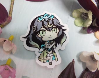 May include: A sticker featuring a cartoon character with long, dark blue hair, wearing a white dress with blue and green accents. The character has a crown on her head and is smiling.