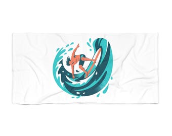 May include: White beach towel featuring a surfer riding a wave. The illustration shows a surfer in blue shorts on a surfboard, with a teal and orange wave design. The towel is rectangular and made of soft fabric.
