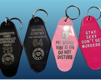 Può includere: Quattro portachiavi neri e rosa a forma di chiavi di camera d'albergo. I portachiavi hanno testi diversi, tra cui "Gringotts Bank", "Hotel Cortez", "My Whole Vibe Is On Do Not Disturb" e "Stay Sexy Don't Get Murdered".