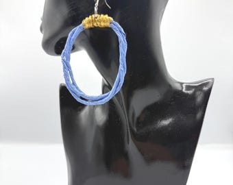 May include: A hoop earring featuring a large, circular, light blue twisted cord frame. The top section of the hoop is wrapped in a metallic gold thread, which connects to a silver-toned metal hook for attachment to the ear.