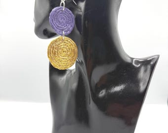 May include: Dangle earrings featuring two stacked circular discs. The top disc is purple and the bottom disc is metallic gold. Both discs have a textured, coiled rope-like appearance. The earrings are attached to silver-toned metal hooks.