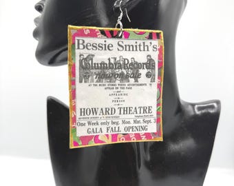 May include: A rectangular dangle earring featuring a vintage advertisement for Bessie Smith at the Howard Theatre. The print is layered over a pink and green patterned background with a gold-colored border and a silver-toned metal ear wire hook.