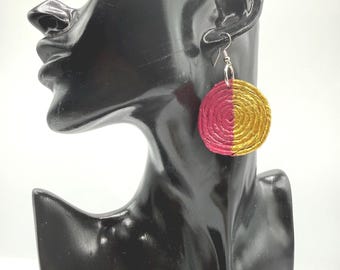 May include: A circular dangle earring featuring a coiled texture with a split color design. One half of the circle is vibrant magenta pink, while the other half is metallic gold. The earring hangs from a silver-toned metal hook wire.