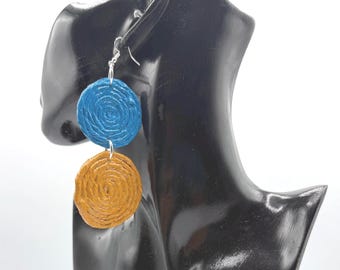 May include: A pair of drop earrings featuring two stacked circular discs with a textured, coiled rope-like pattern. The top disc is a vibrant blue, while the bottom disc is a warm mustard yellow. The earrings are attached with silver-toned hooks.