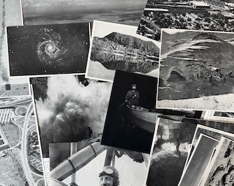 May include: A collection of black and white photographs, including images of a galaxy, a mountain reflected in water, a waterfall, a man in a boat, and an aerial view of a city. The photographs are arranged in a layered composition.