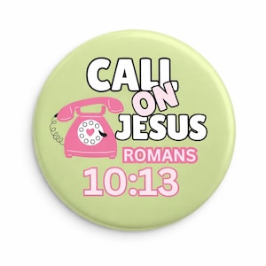 May include: A round, light green button with the words "CALL ON JESUS" in black and pink. A pink telephone with a heart-shaped dial is on the left. The text "ROMANS 10:13" is below the main text.