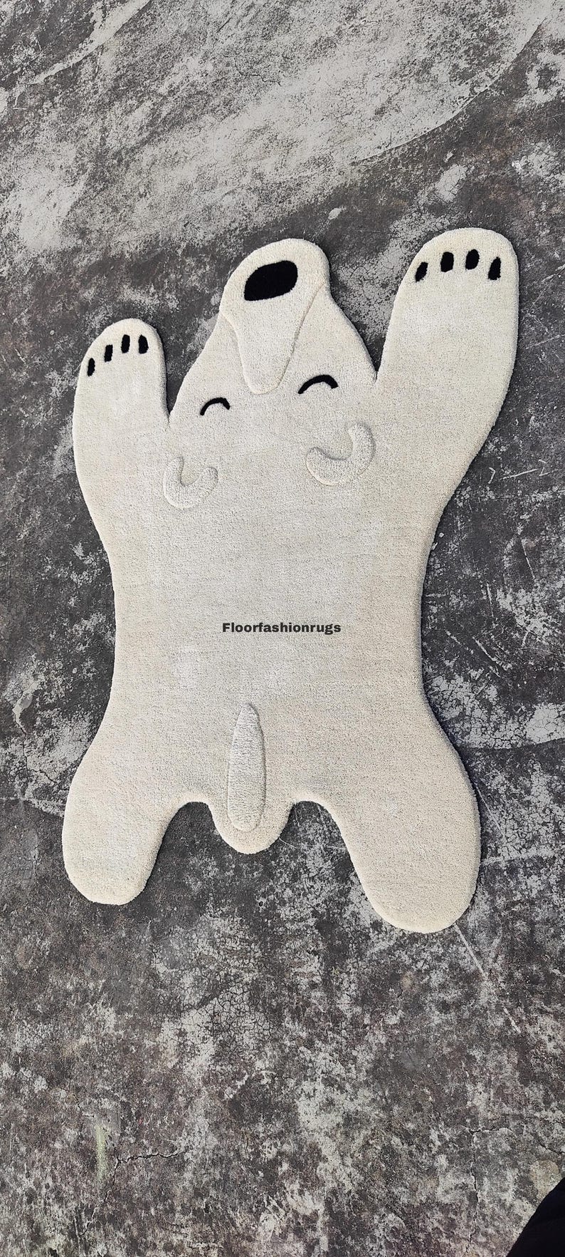 May include: A cream-colored, plush rug shaped like a cartoon bear with a smiling face and black accents. The rug has a playful design, with the text "floorfashionrugs" visible.