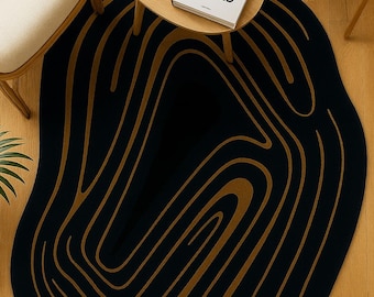 Pode incluir: Um tapete preto e dourado com um design abstrato. O tapete tem um fundo escuro com linhas curvas douradas. Uma pequena mesa redonda de madeira tem uma caneca branca e um livro intitulado "100 Interiors Around the World".