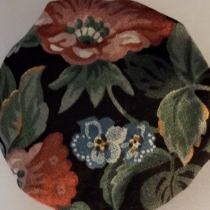 May include: A black fabric with a floral pattern featuring red, pink, blue, and green flowers. The fabric has a textured surface.