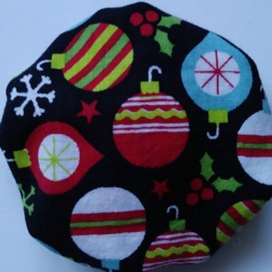 May include: A black Christmas-themed fabric with colorful ornaments, snowflakes, and holly. The ornaments are red, green, white, and blue with various striped and star designs. The fabric is likely used for holiday crafts or decor.
