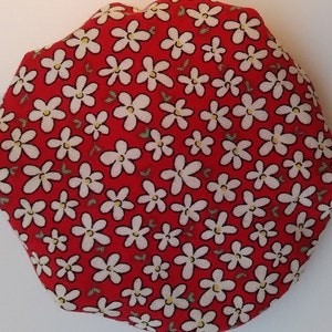 May include: Red fabric with a white daisy pattern. The fabric is circular and has a textured surface.