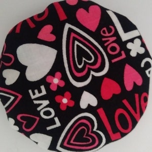 May include: Black fabric with a repeating pattern of pink, white, and red hearts and the word "LOVE" in white.