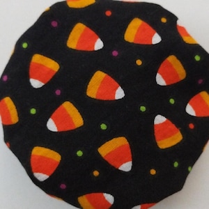 May include: Black fabric with a repeating pattern of orange and white candy corn on a black background with small multi-colored dots.