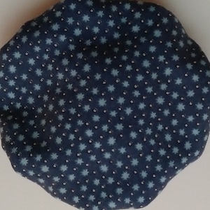 May include: A navy blue, irregularly shaped fabric item with a repeating pattern of light blue star-like shapes and small white dots. The fabric appears to be soft and possibly cotton.